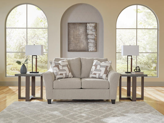 Beige accent chair with patterned pillows in a living room with arched windows