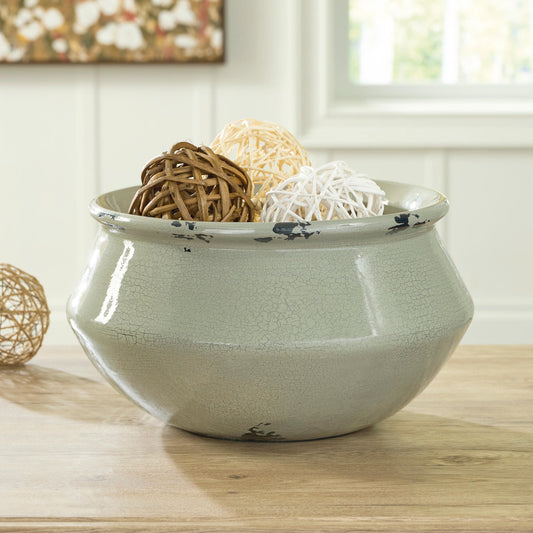 Green decorative bowl filled with decorative objects on a table