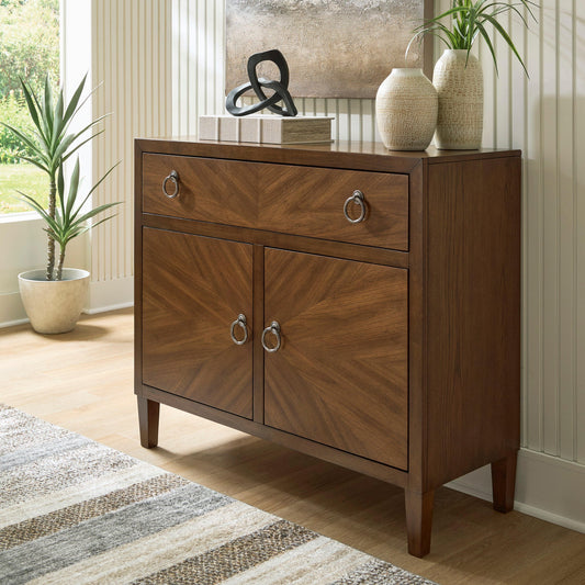 Brown wooden cabinet styled with framed artwork and decorative objects