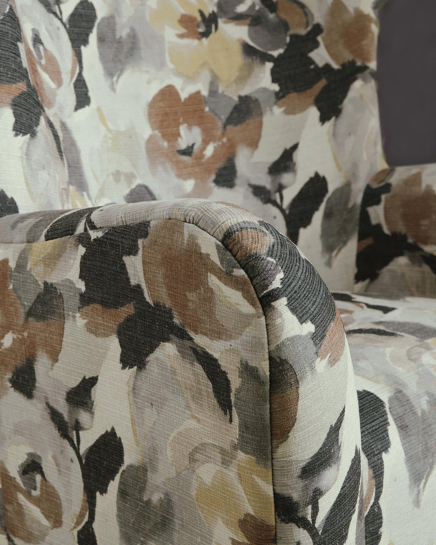 Close-up of a floral accent chair's upholstered arm and seat