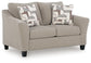 Beige upholstered accent chair with patterned pillows, angled view