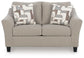 Beige upholstered accent chair with patterned pillows, front view