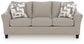 Beige loveseat with patterned accent pillows, front view