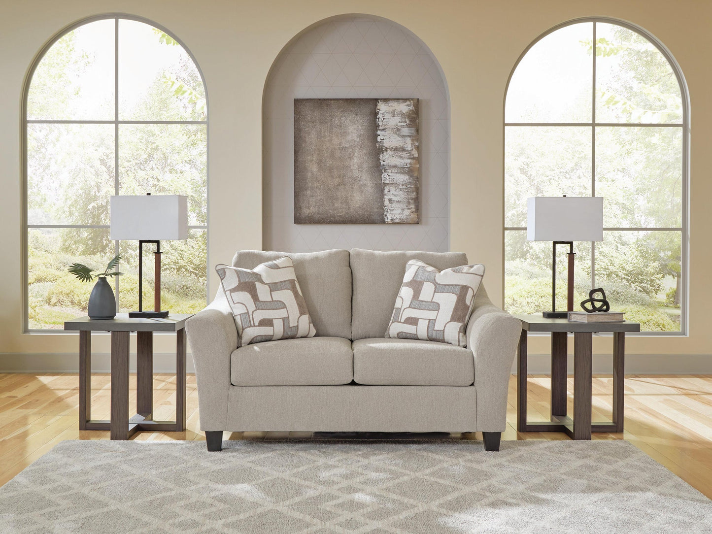 Beige accent chair with patterned pillows in a living room with arched windows