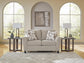 Beige accent chair with patterned pillows in a living room with arched windows