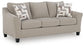 Beige loveseat with patterned accent pillows, angled view