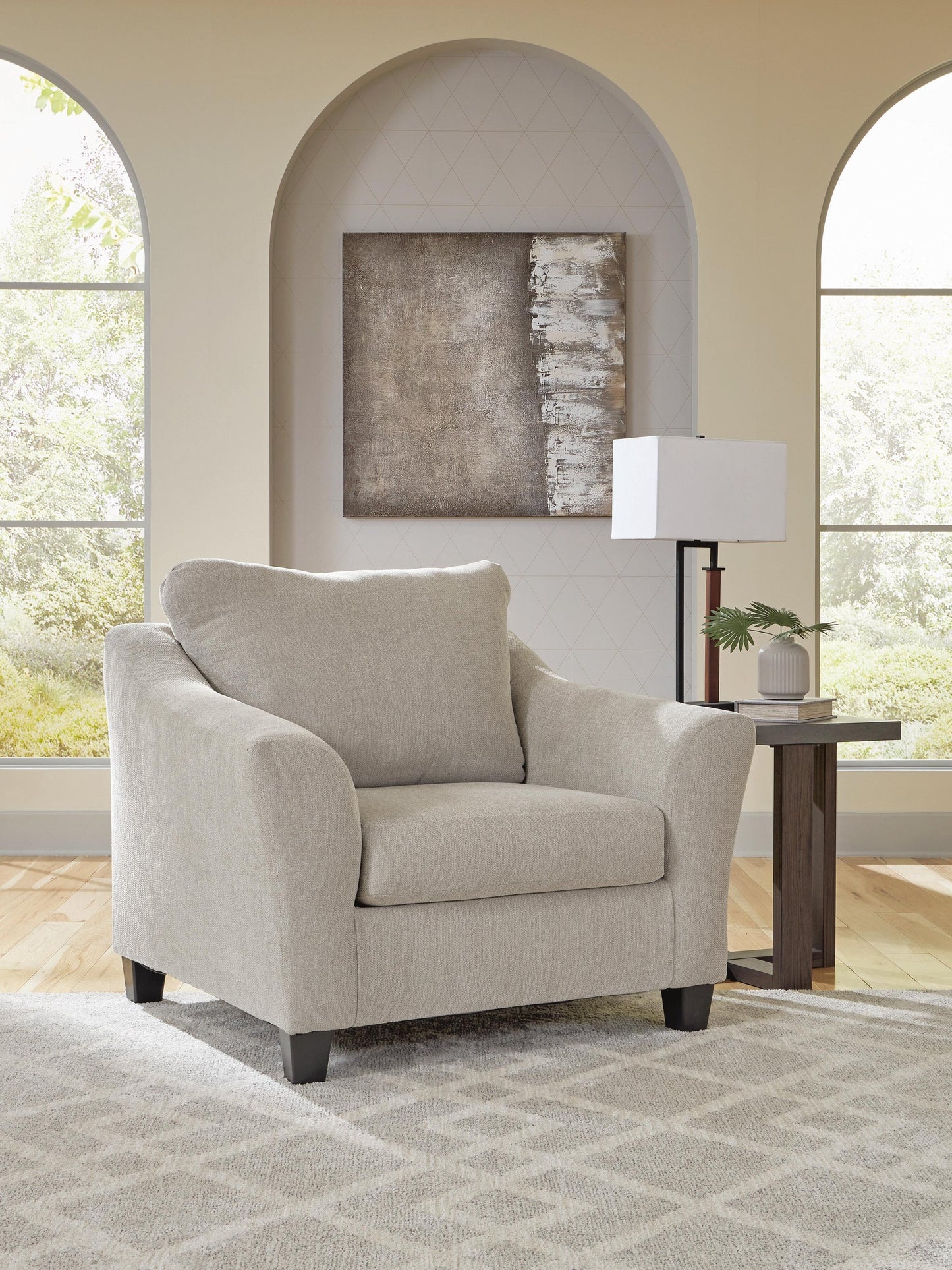 Beige upholstered armchair beside an accent table in a bright living room
