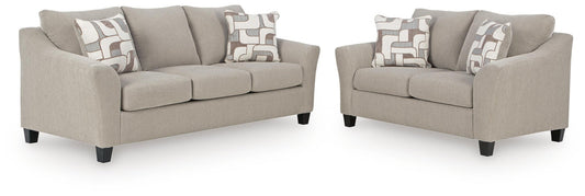 Beige sofa and matching loveseat with accent pillows against a white background